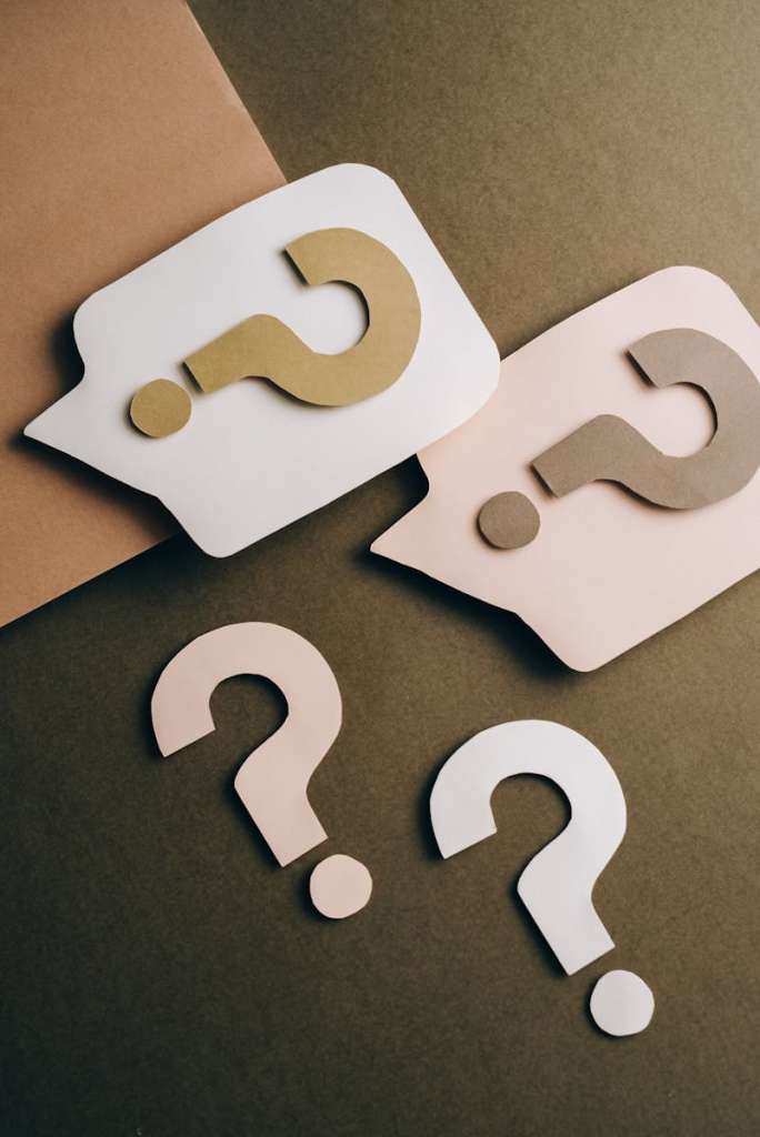 Artistic paper cutouts of question marks creating a conceptual design on a brown surface.